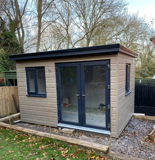 Light brown outdoor building with black door and windows.