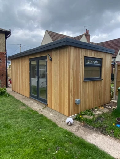 Wooden outdoor building next to garden.