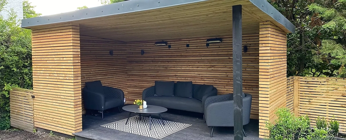 Wooden outside building with black seating and supporting pole.