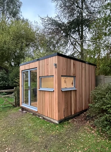 Wooden outdoor building next to some trees.